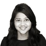 Portrait of a person smiling with long, dark hair, wearing a dark top, against a plain white background.