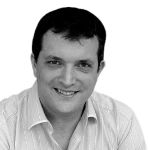 Smiling person in a light striped shirt against a white background.