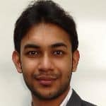 A person with short dark hair, a goatee, and a slight smile, wearing a dark jacket and white shirt, in front of a plain white background.