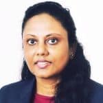 A woman with dark hair, wearing a dark blazer and maroon top, poses in front of a plain white background.